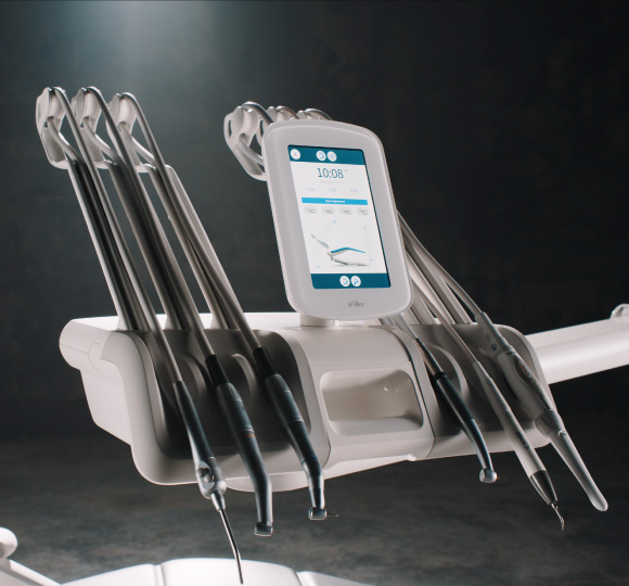 An A-dec 500 Pro delivery system with dental tools and an A-dec+ enabled DS7 touchpad lie on a grey background.